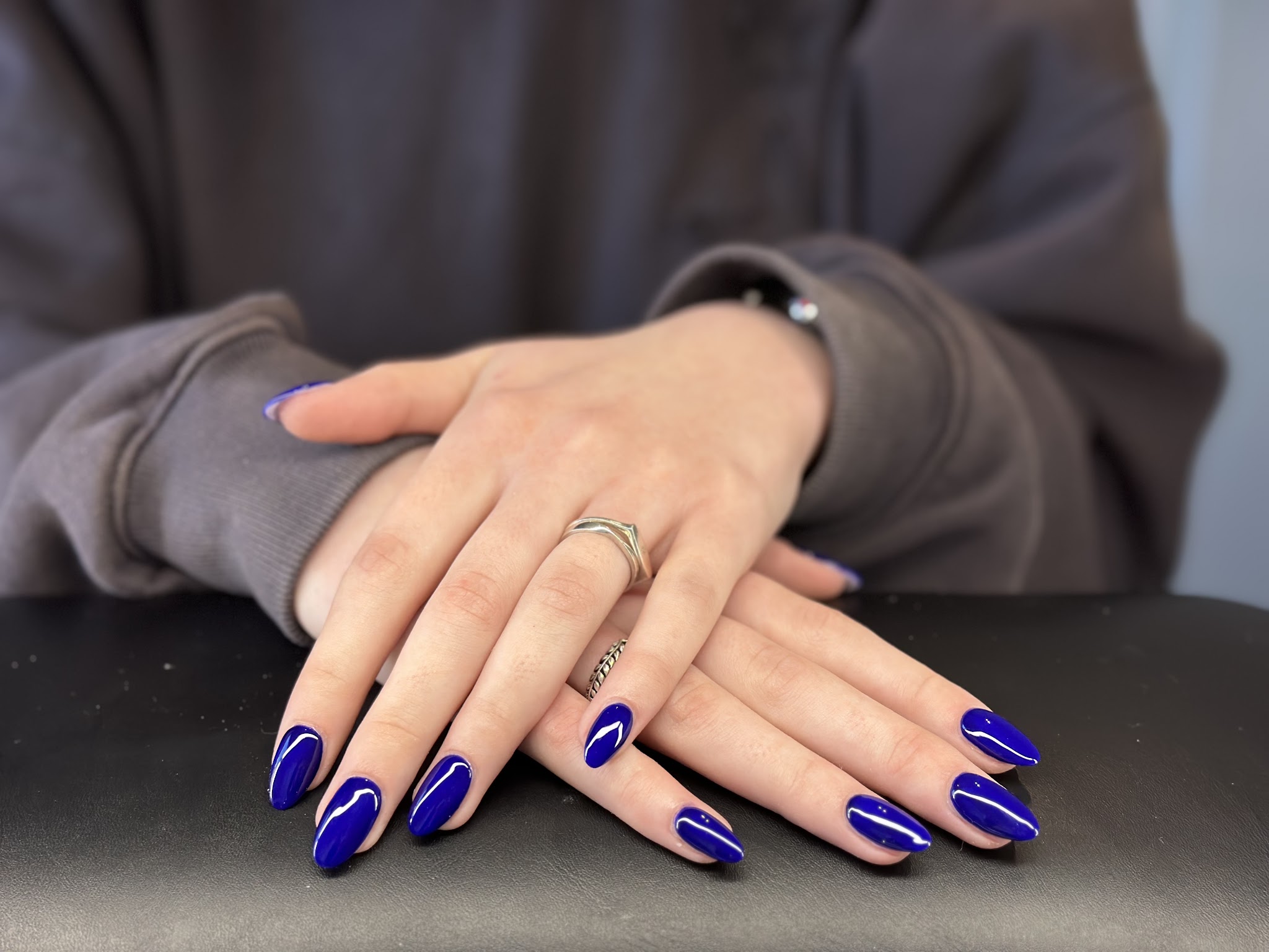 Kobaltblauwe amandelnagels op de zwarte armleuning