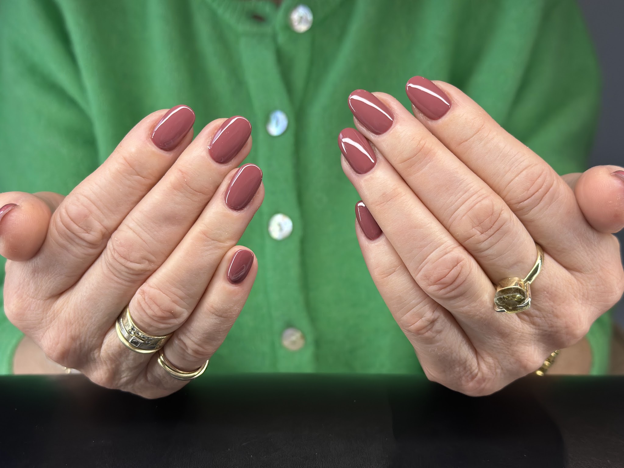 Nagels in mauve, beide handen open voor een groen vest