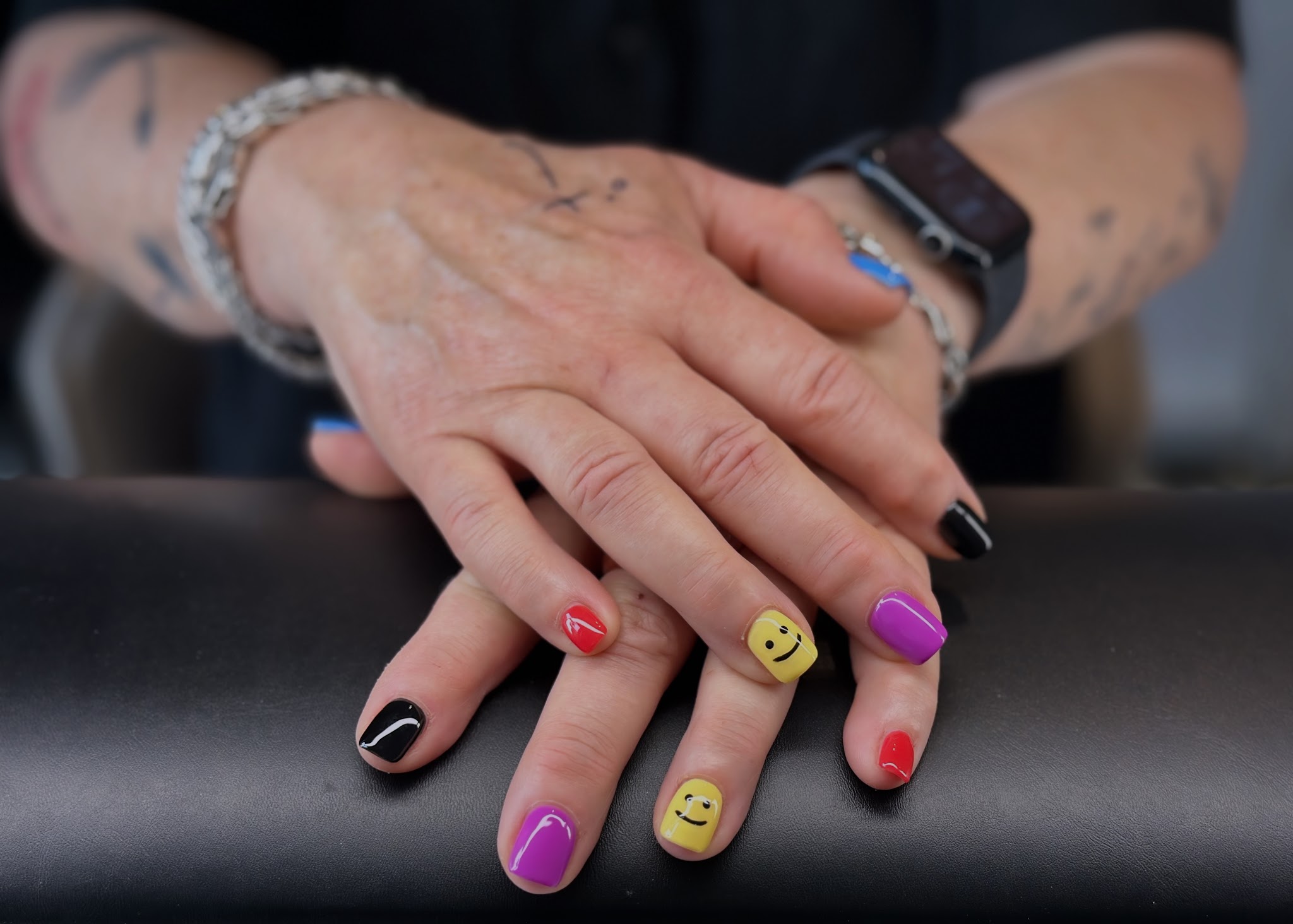 Kleurrijke nailart met smileys in geel, rood, paars en zwart